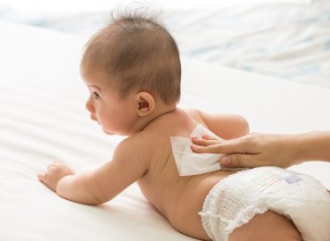 Mother cleaning up and wipes body and leg baby by wet tissue